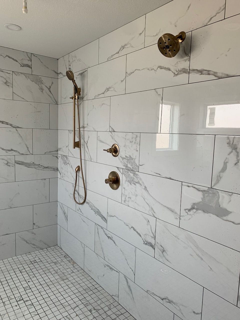 A bathroom with marble tiles and a shower head