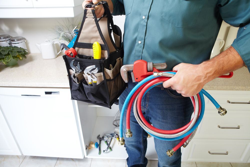 A plumber is holding a hose and a tool bag