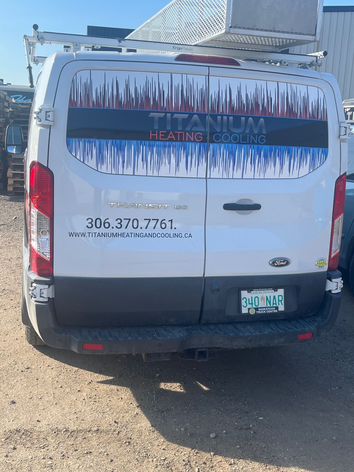 A titanium heating and cooling van is parked in a dirt lot.