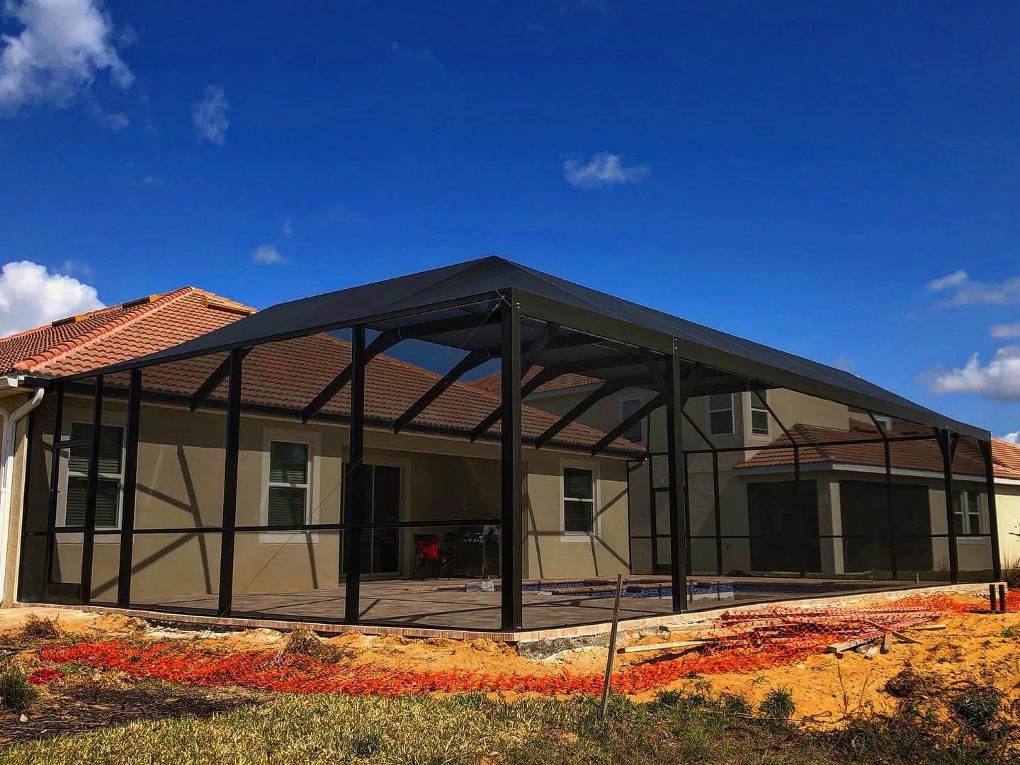 Screened-in patio extension attached to a house with a clear blue sky background.