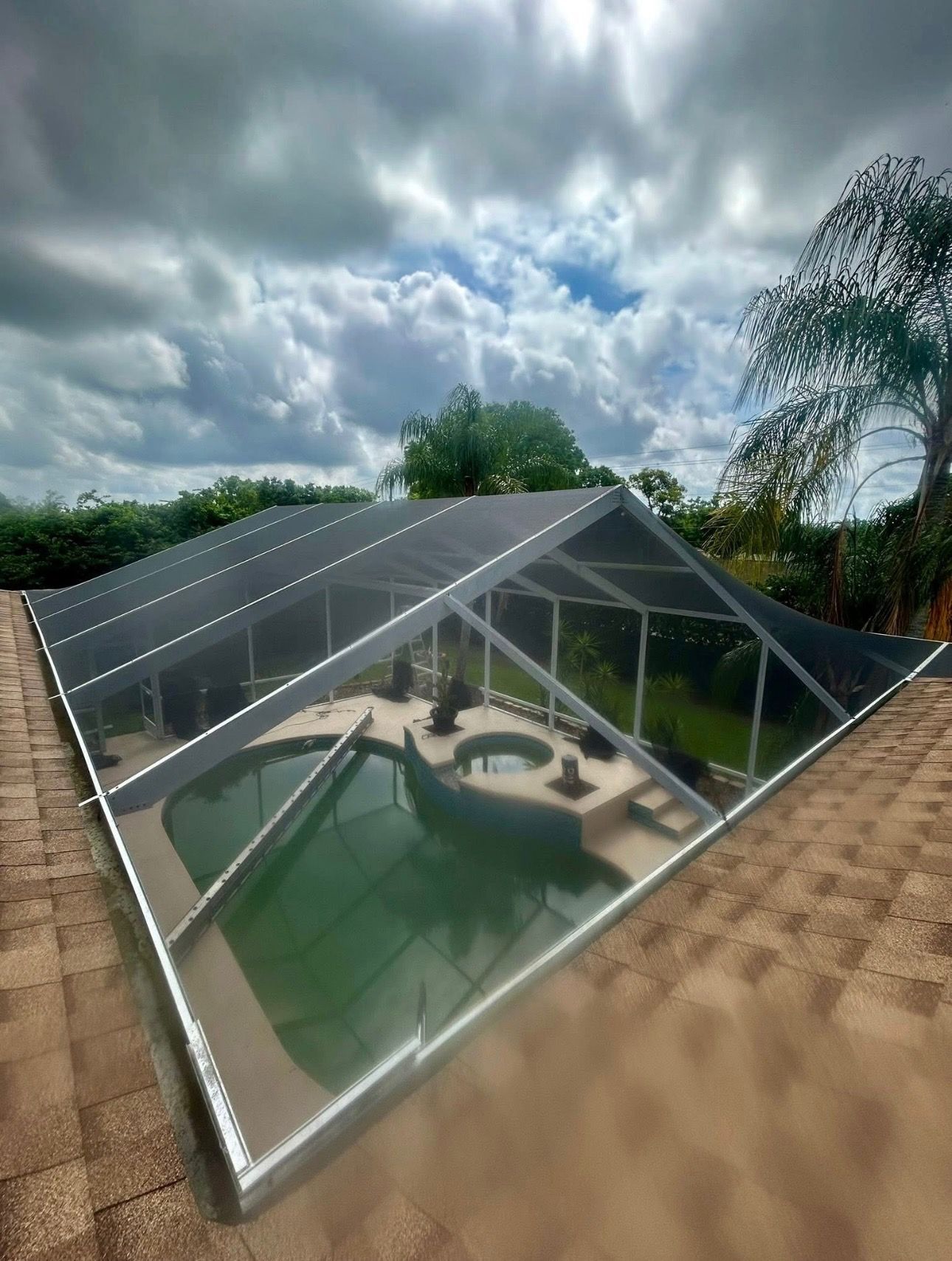 Black dump trailer parked in front of a blue house with a white garage door.