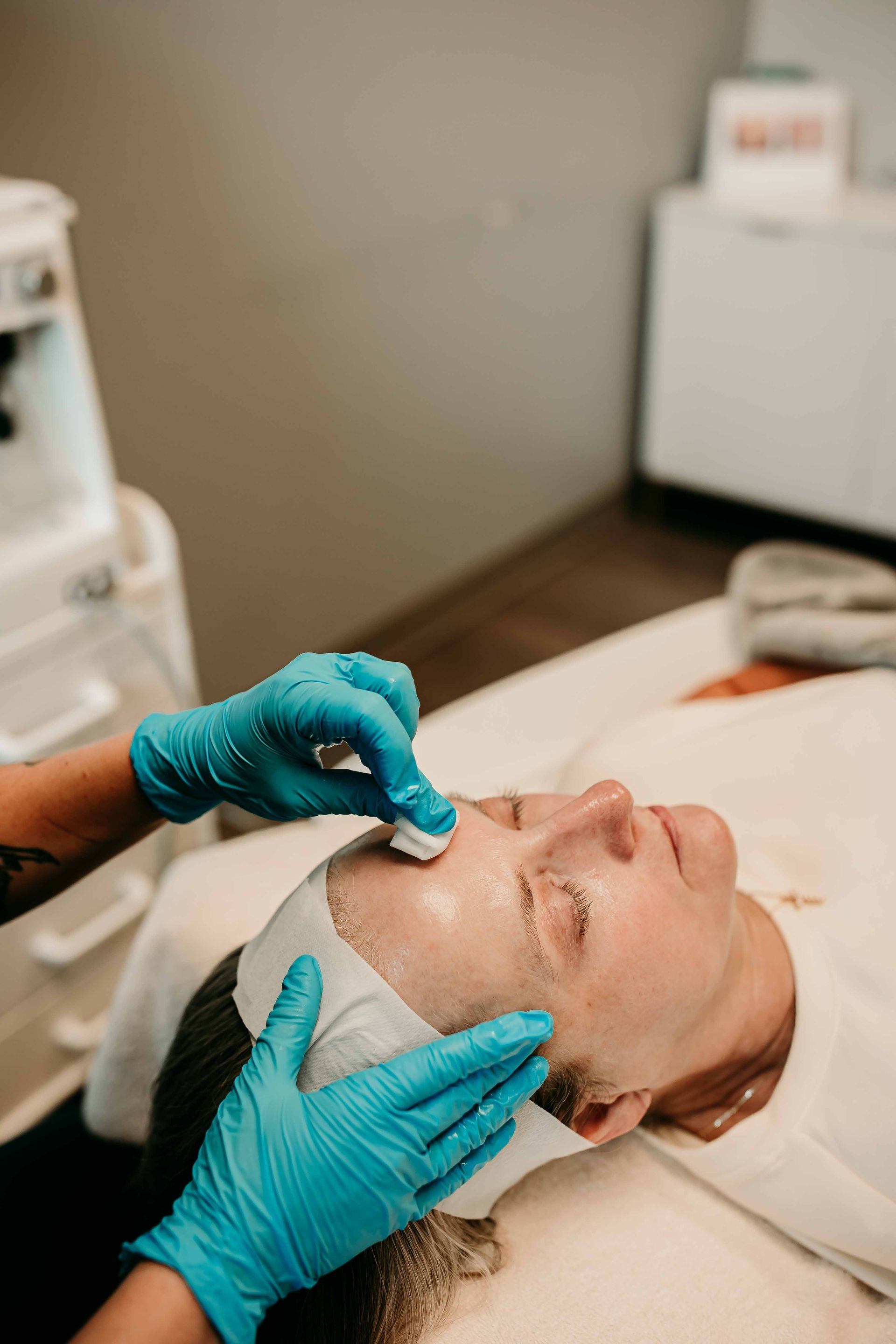 A person receiving a facial treatment in a spa, with gloved hands applying a product.