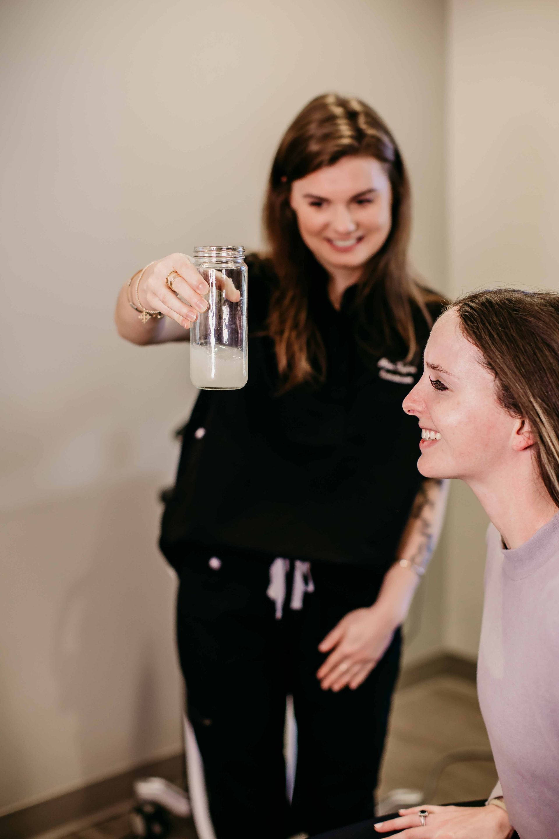 A woman is holding a glass of milk in front of another woman.