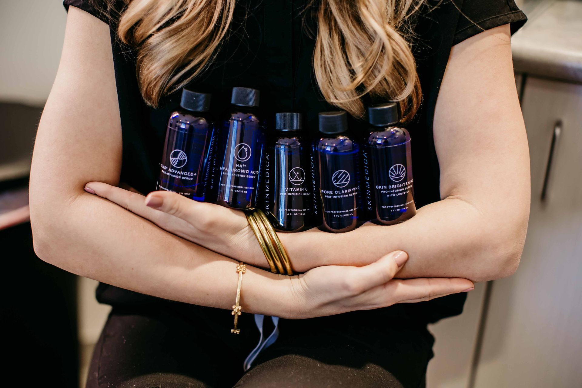 A woman is holding a row of small bottles in her hands.