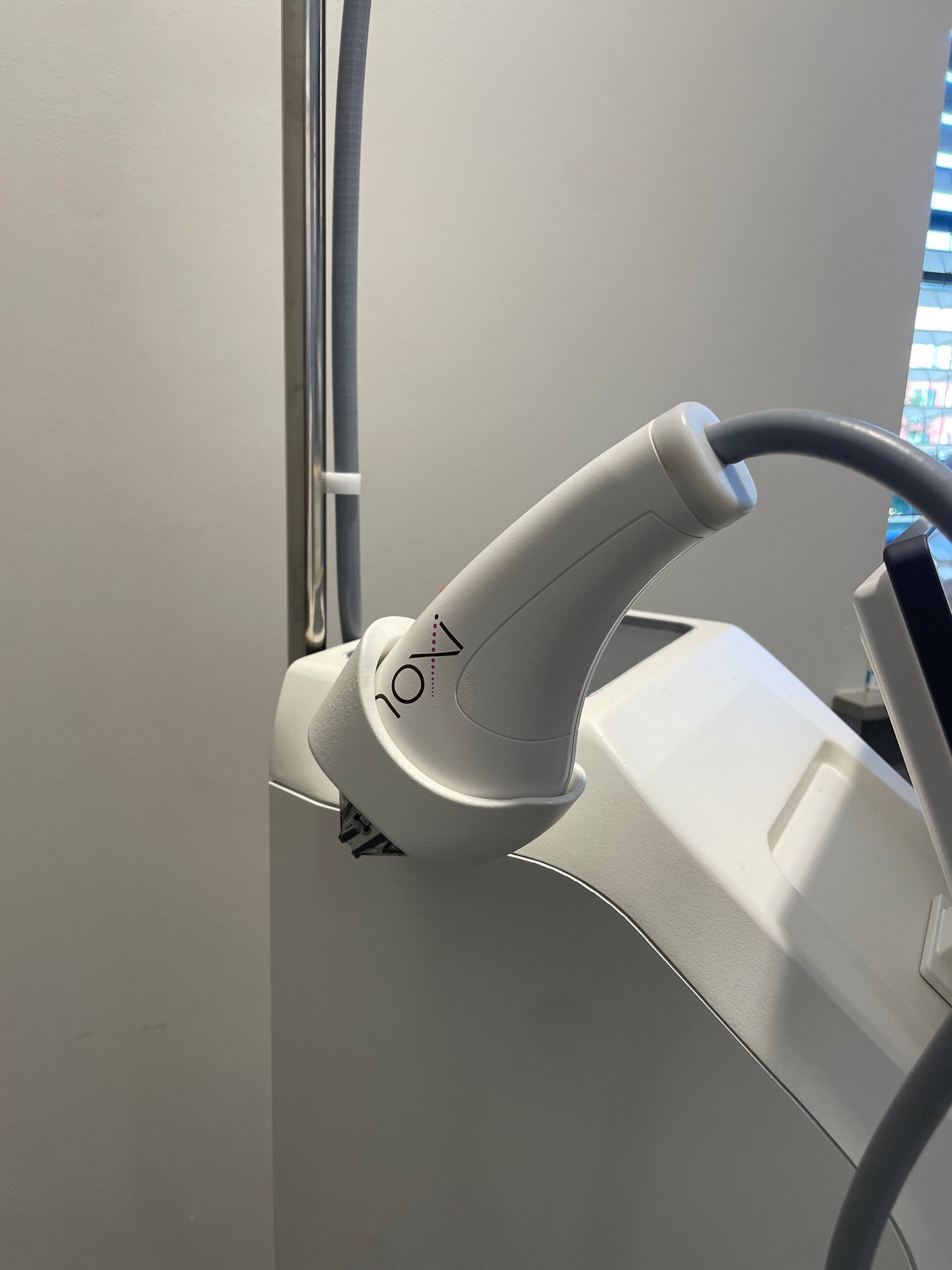 White medical device head with cord, mounted on a wall.