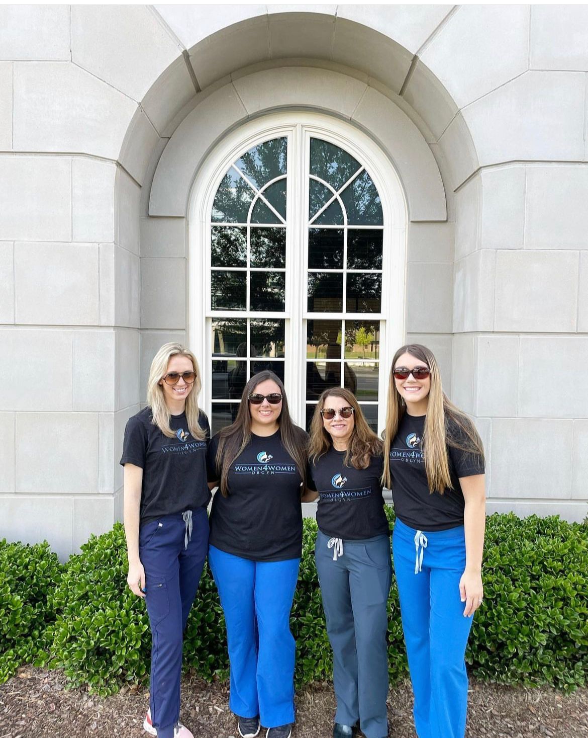 Four women are posing for a picture in front of a building.