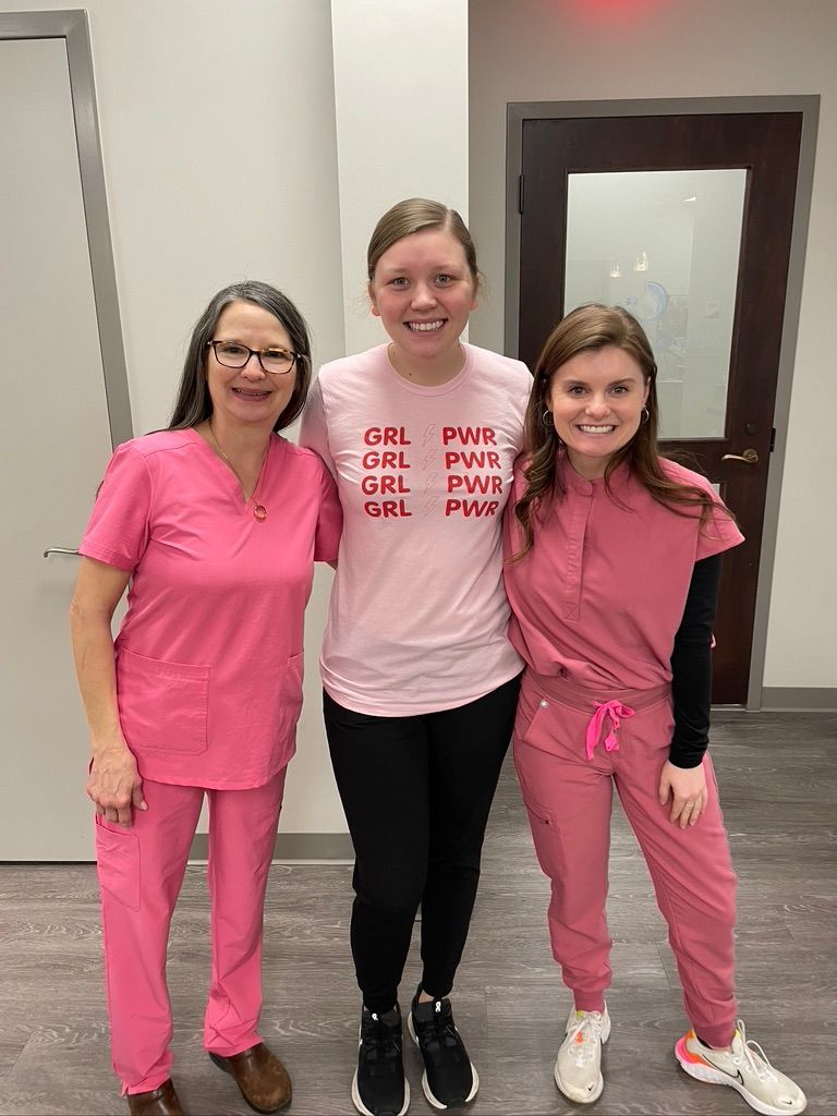 Three women in pink scrubs are posing for a picture.