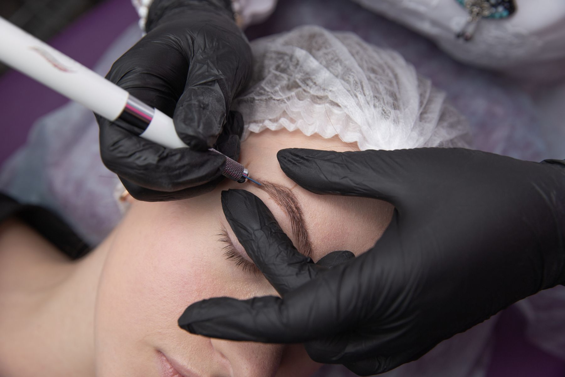 A woman is getting permanent makeup on her eyebrows.