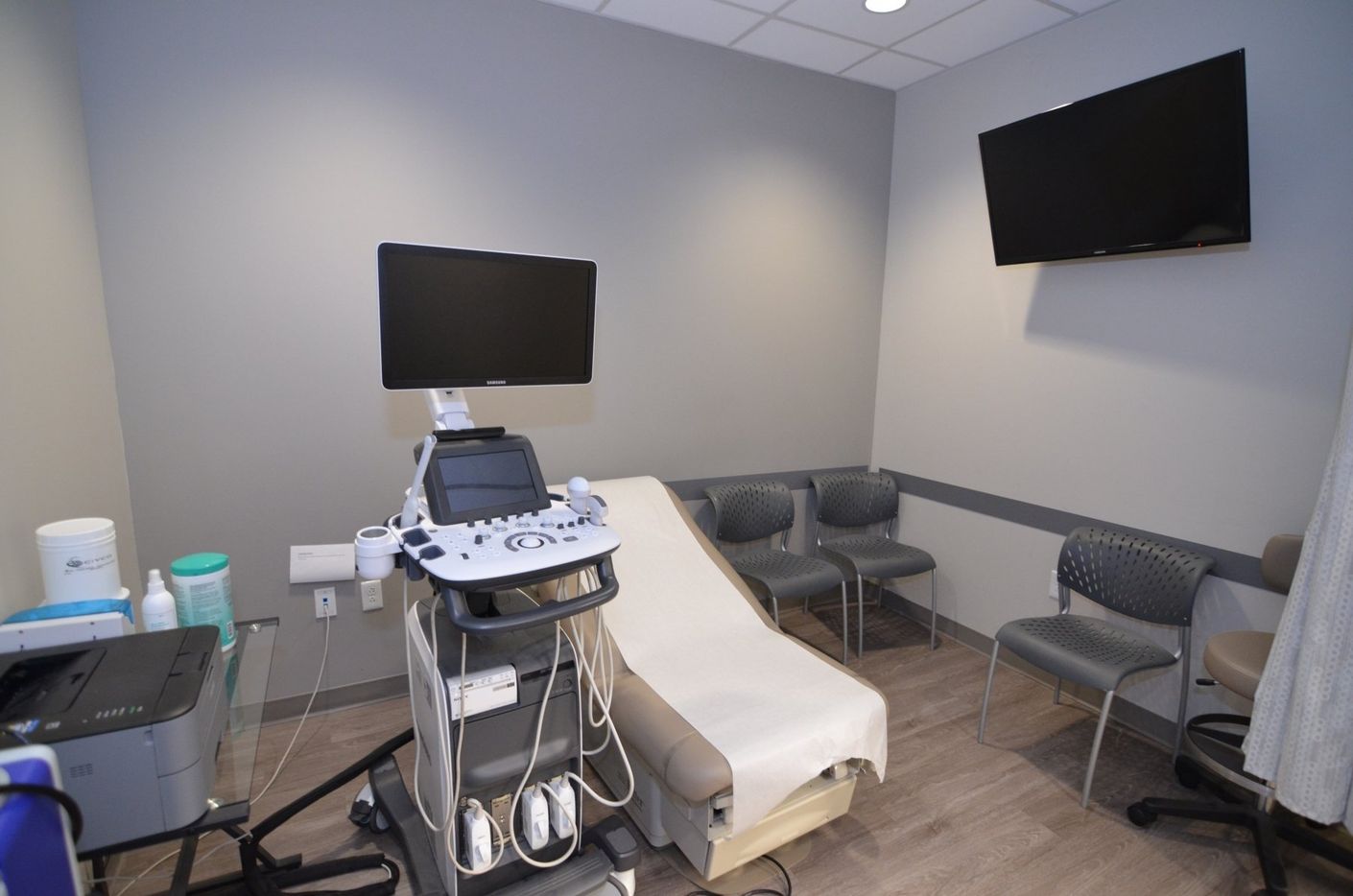 A doctor 's office with an ultrasound machine and a television.