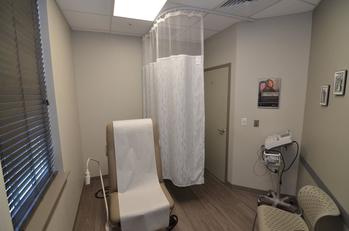 A doctor 's office with a chair and a curtain.