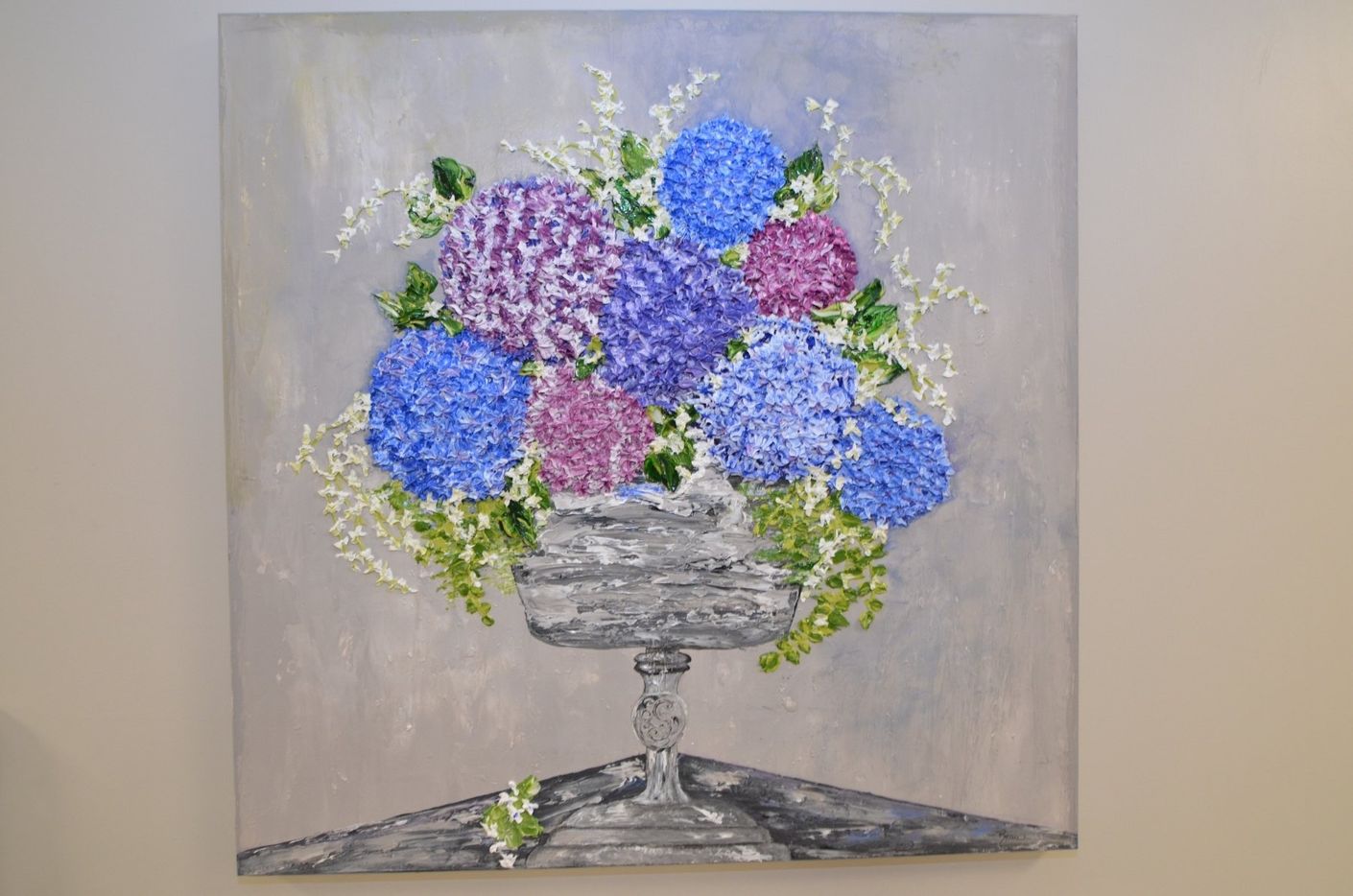 A painting of purple and blue flowers in a vase on a table