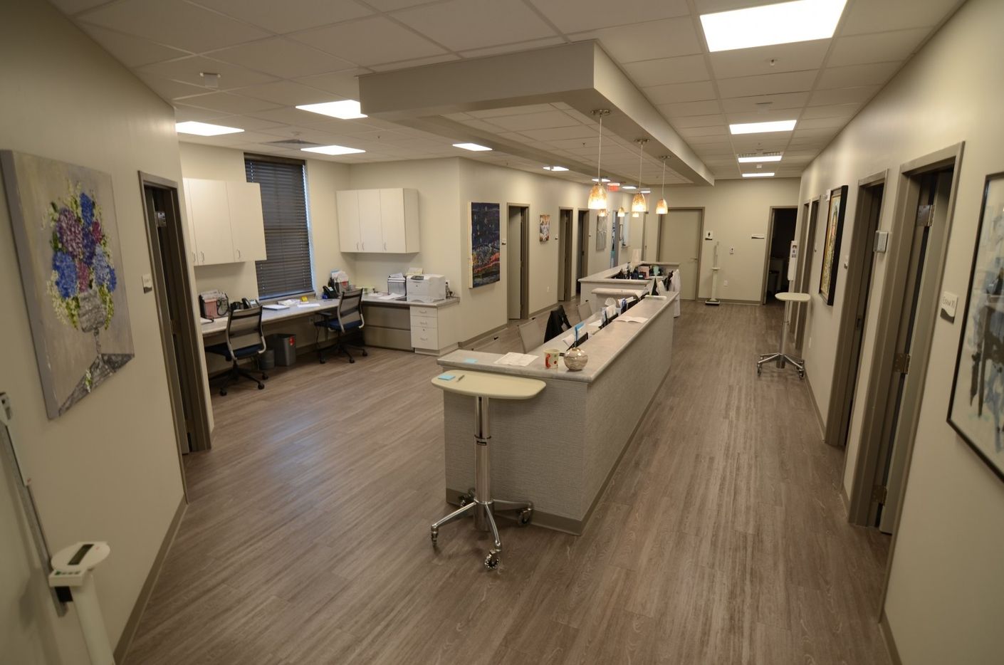 A long hallway with a desk and chairs in a hospital.