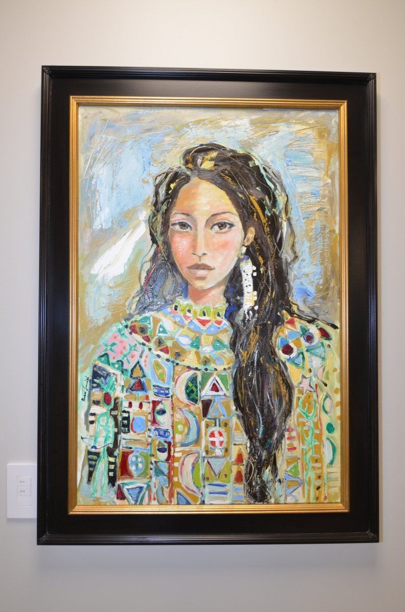 A painting of a woman with long hair is hanging on a wall.