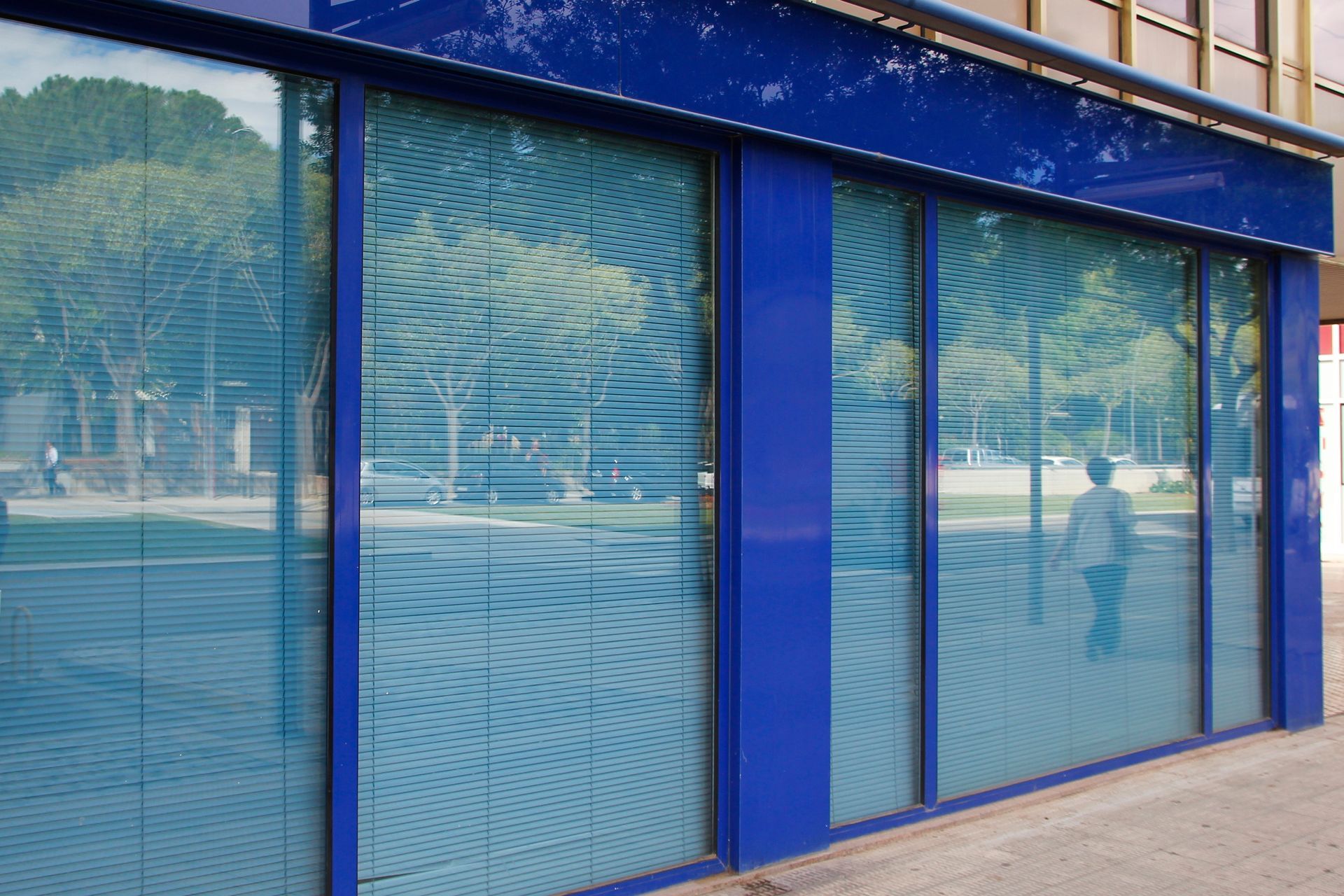 Blue storefront with reflective glass windows and a closed door along a sidewalk Blue storefront with reflective glass windows and a closed door along a sidewalk