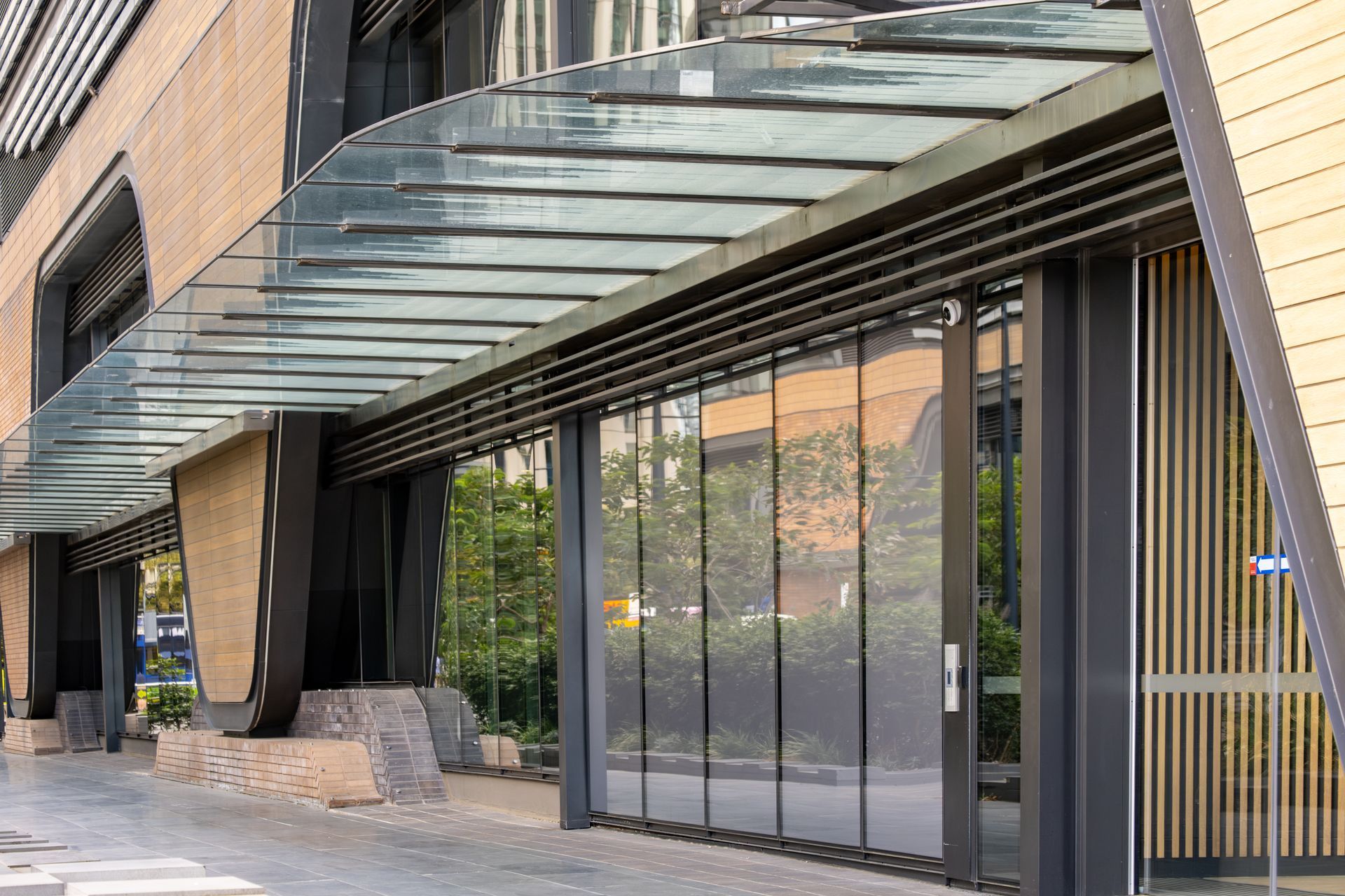 Modern storefront with glass doors, black columns, and a glass canopy along a sidewalk Modern storefront with glass doors, black columns, and a glass canopy along a sidewalk