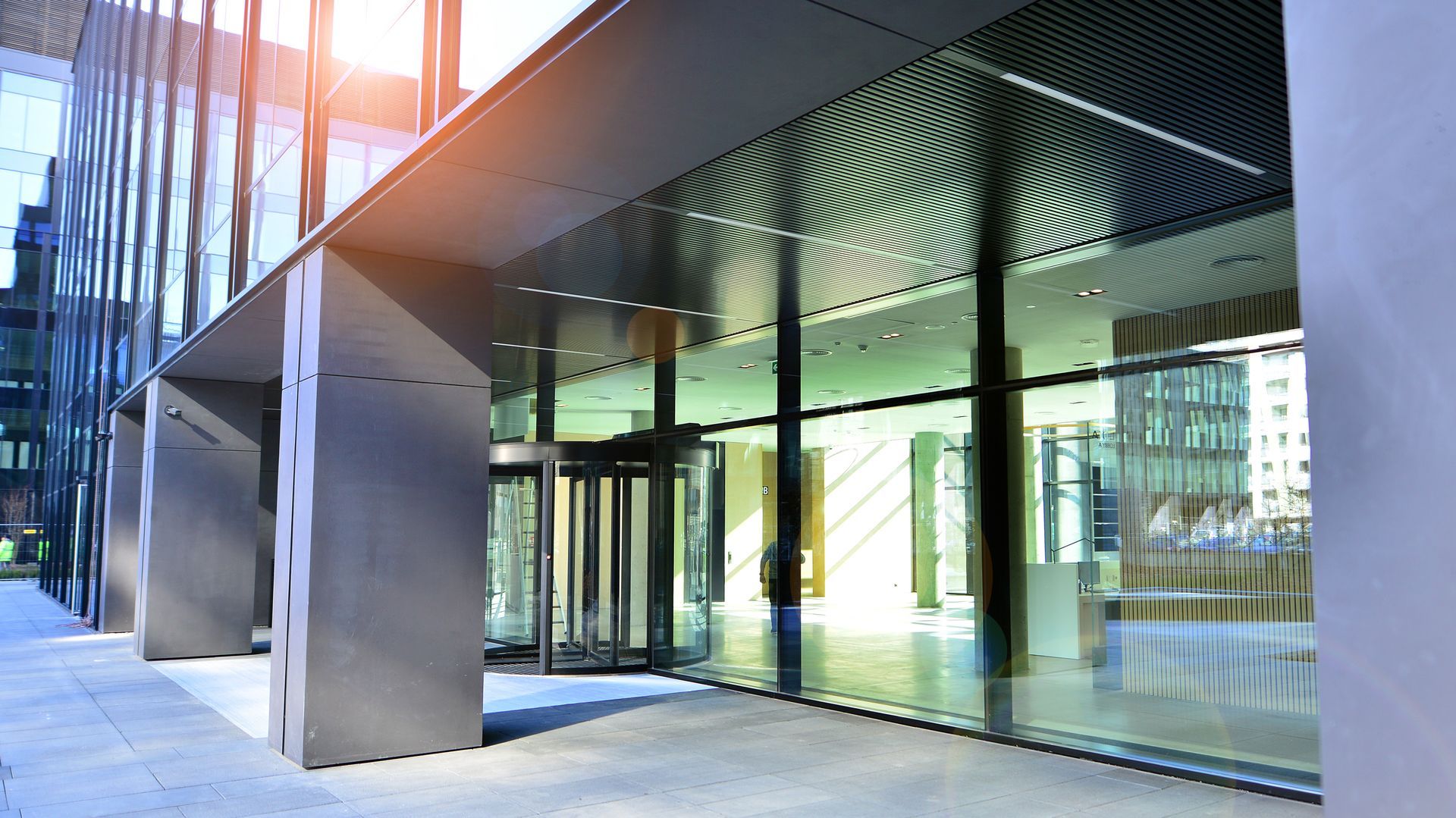 Modern glass office building entrance with metal canopy and revolving door Modern glass office building entrance with metal canopy and revolving door