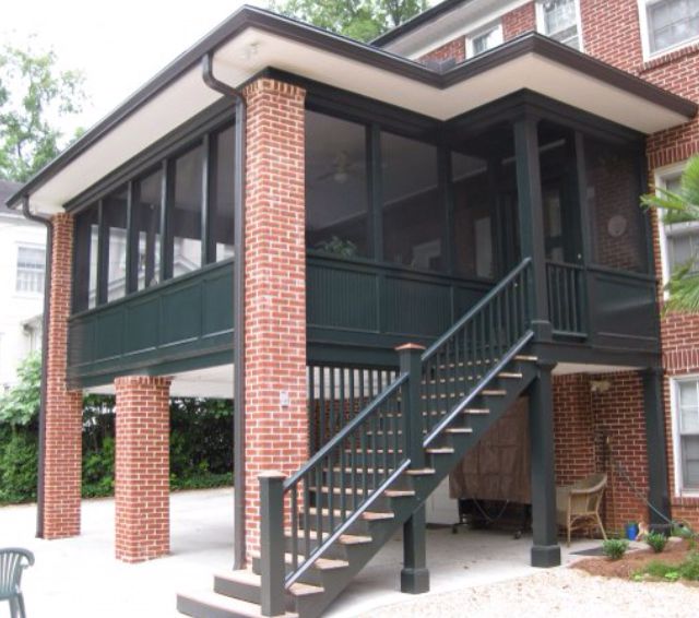 A brick house with a screened in porch and stairs