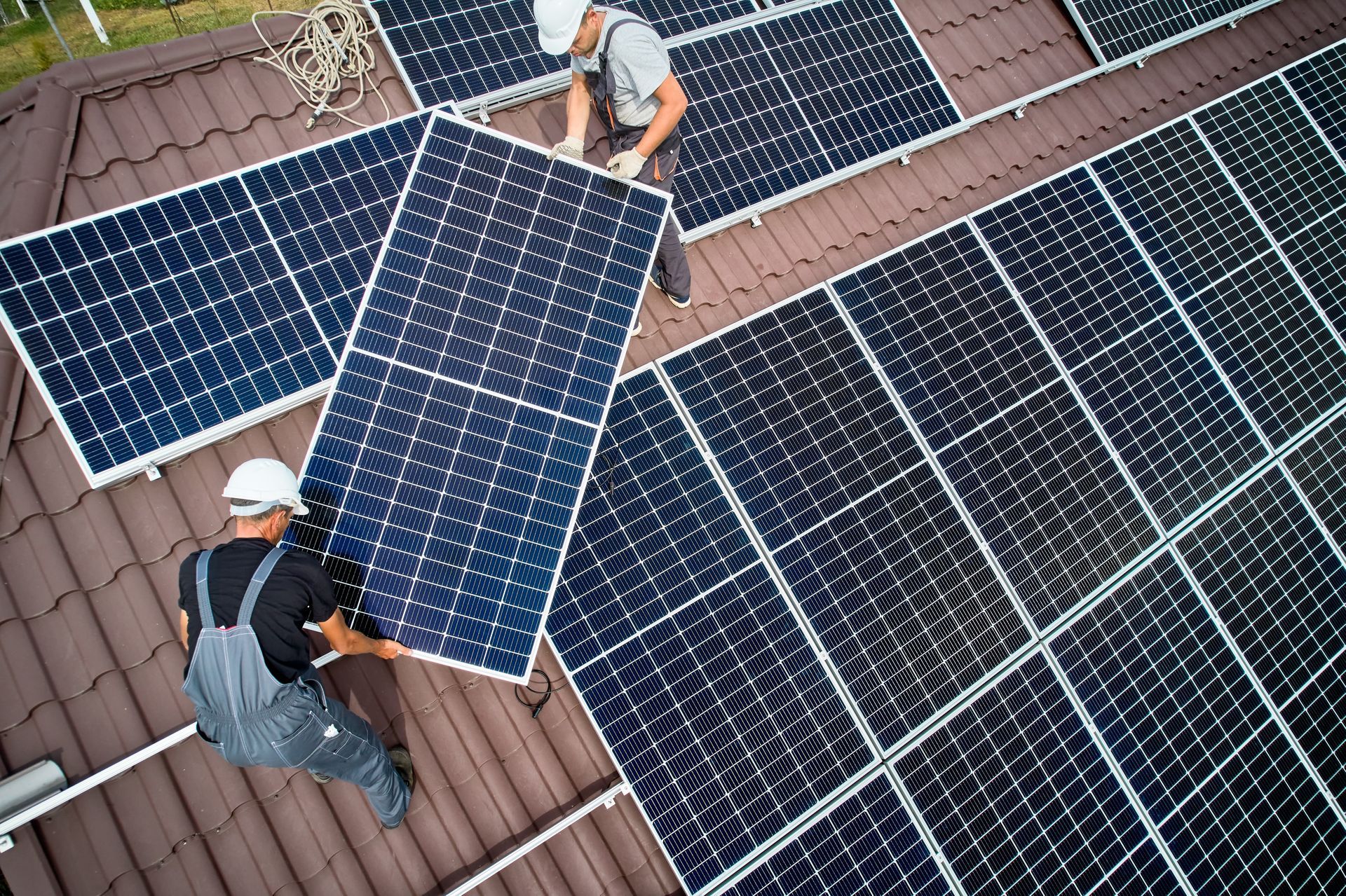 Two men are installing solar panels on the roof of a house.