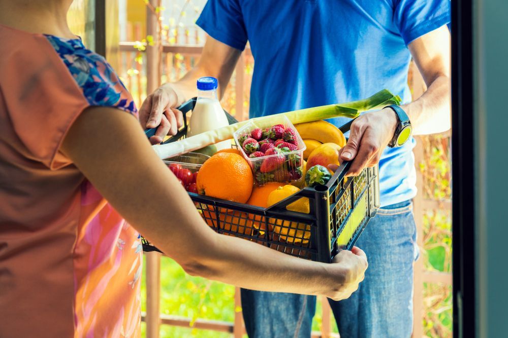 A Man is Delivering a Basket of Fruits and Vegetables to a Woman — Howard Springs Supermarket In Howard Springs, NT