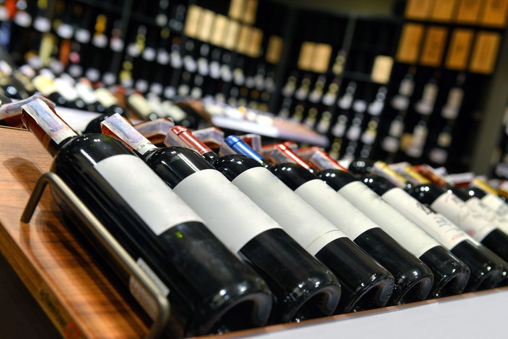 Bottles of Wine Are Lined Up on a Wooden Shelf in a Store — Howard Springs Supermarket In Howard Springs, NT