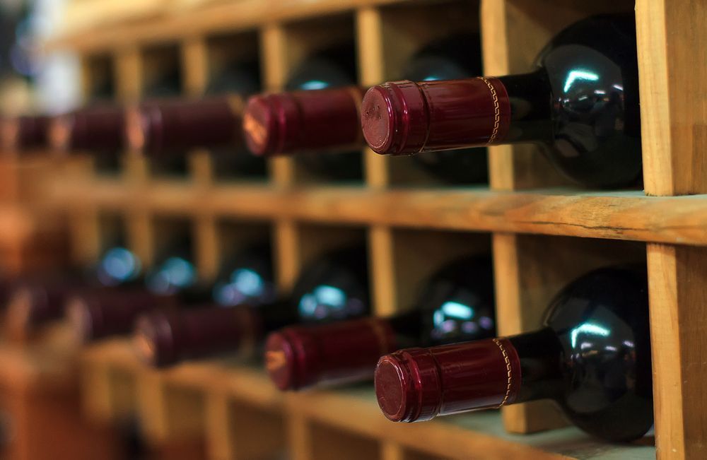 A Row of Wine Bottles Sitting on Wooden Shelves in a Wine Cellar — Howard Springs Supermarket In Howard Springs, NT