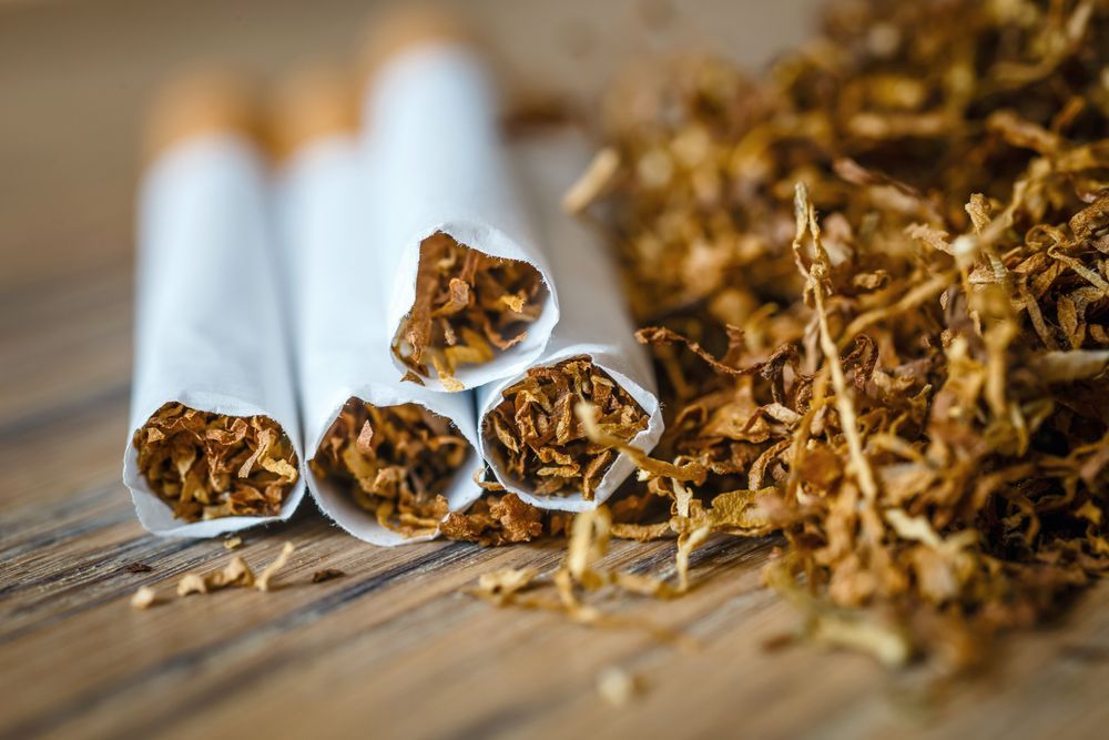 A Pile of Cigarettes and Tobacco Leaves on a Wooden Table — Howard Springs Supermarket In Howard Springs, NT