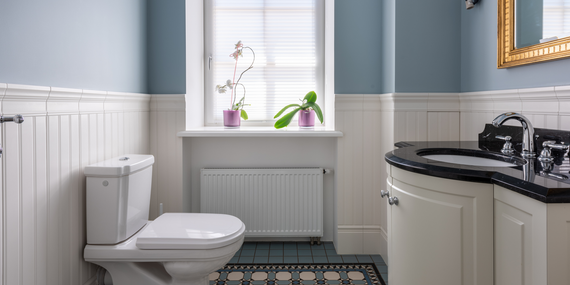 A bathroom with a toilet , sink , mirror and window.
