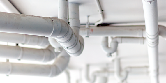 A bunch of white pipes hanging from the ceiling of a building.
