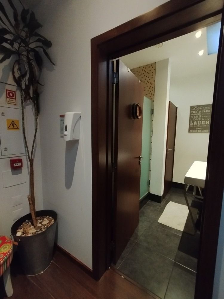 Open office doorway with dark wood door, white walls, potted plant, and a small room visible inside.