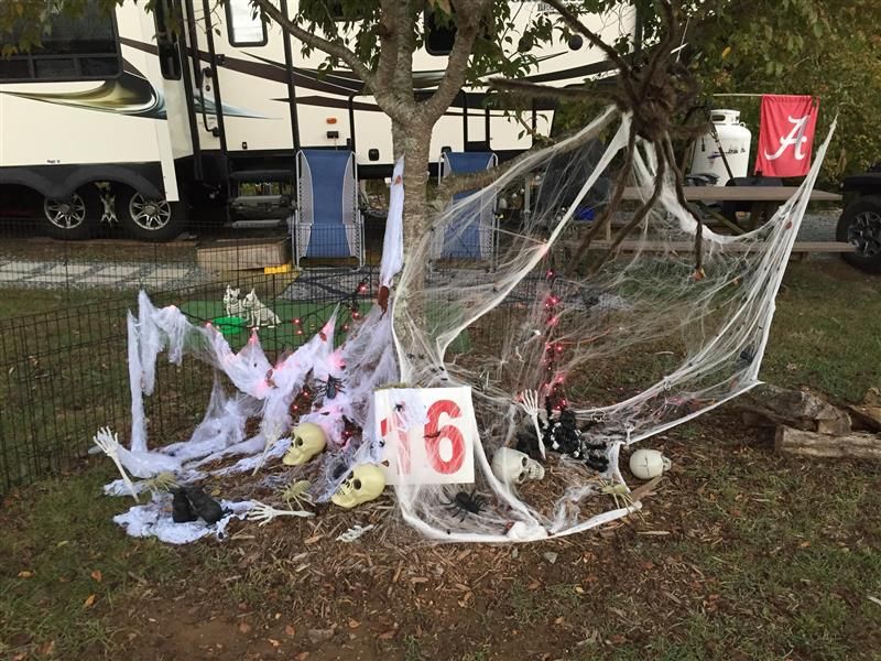 Halloween campsite decorated with fake cobwebs, skulls, and a number 6. A trailer is in the background.