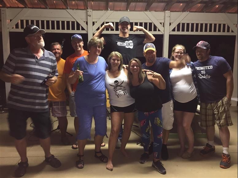 Group of people posing under a gazebo at night. They are smiling and have various poses.