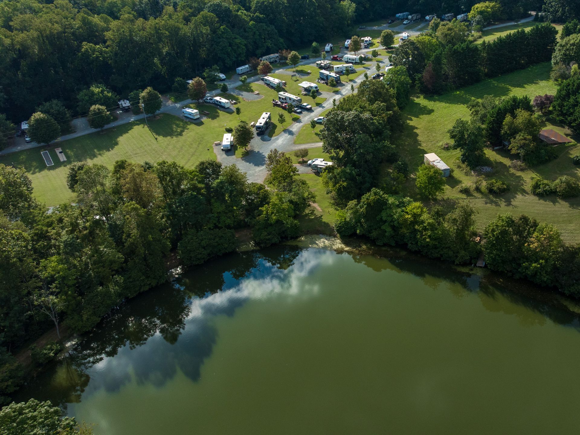 Person riding a teal and orange jet ski on a blue body of water. Lush green trees in the background.