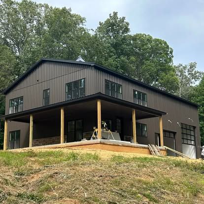 A large metal house with a porch is sitting on top of a hill.