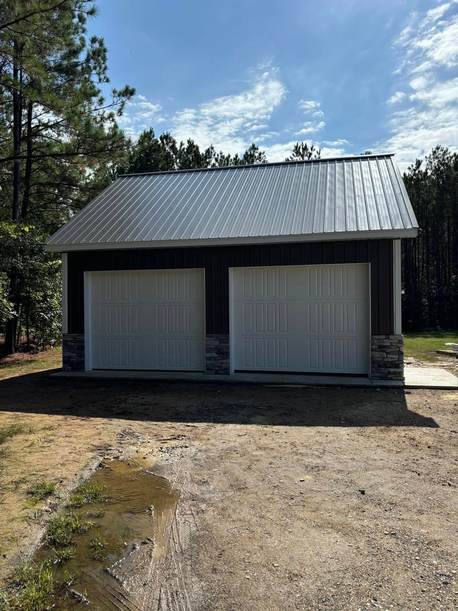 A pole barn garage with two garage doors and a metal roof.