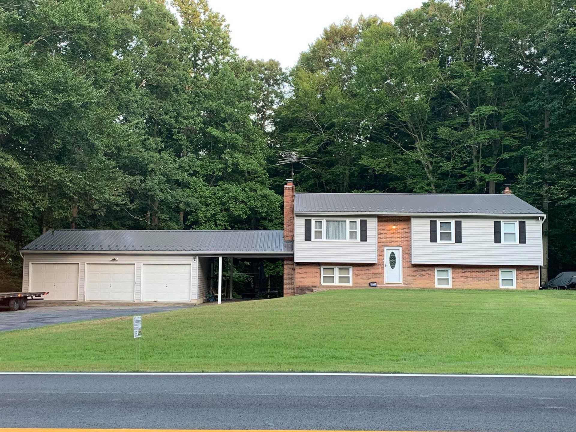 A brick house, a garage and a covered porch with metal roofing