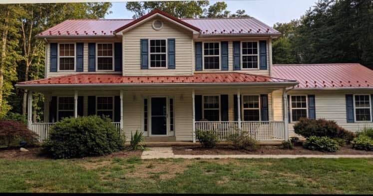 A large white house with blue shutters and a red metal roof.
