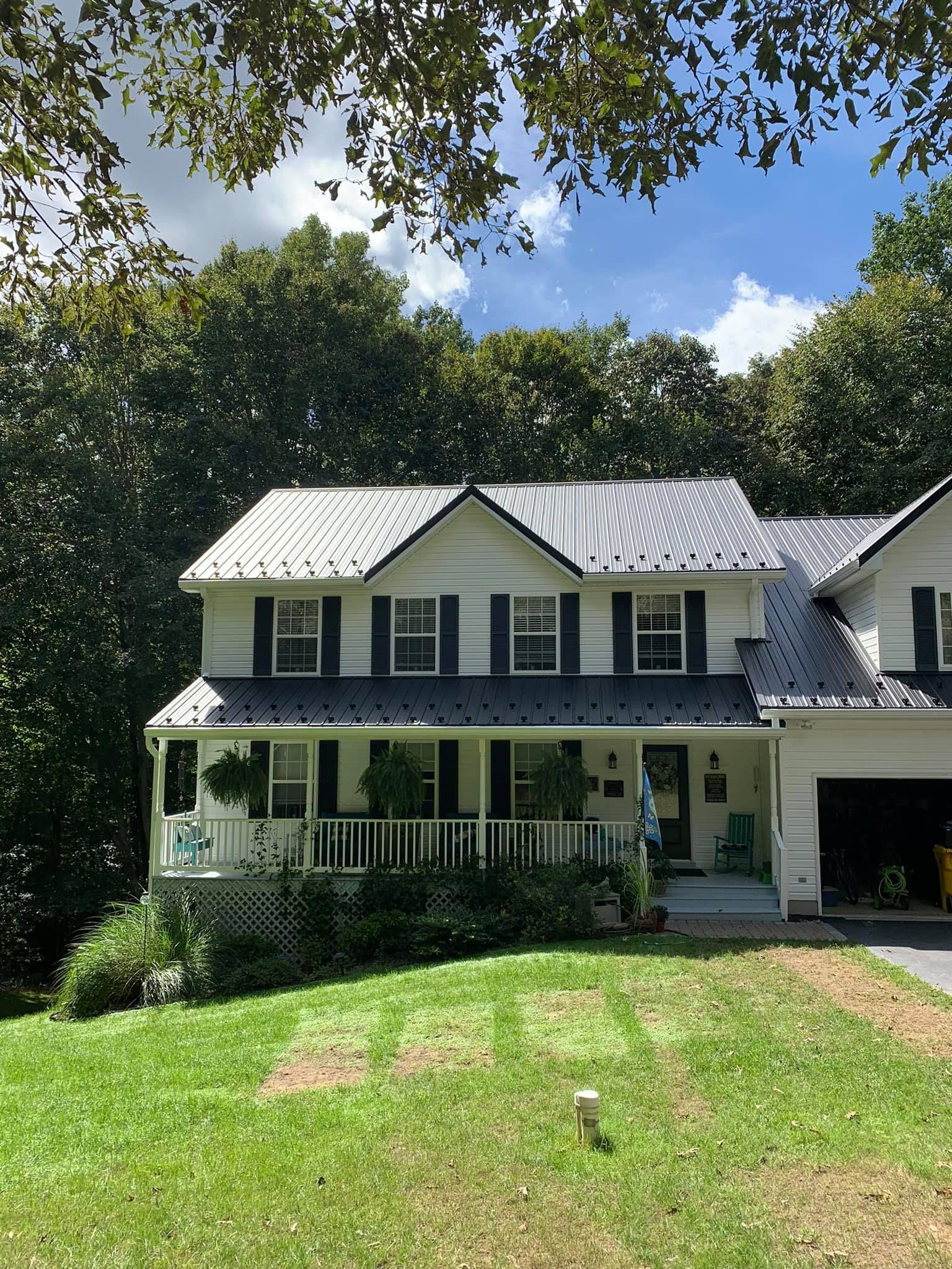 A white house with a gray metal roof by Backroad Construction