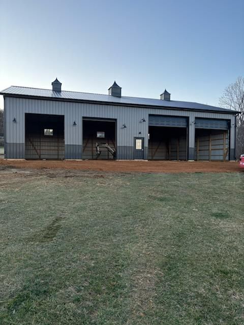 A large barn with a lot of doors and a car parked in front of it.