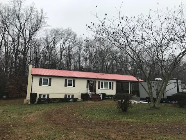 A white house with a red roof is surrounded by trees.