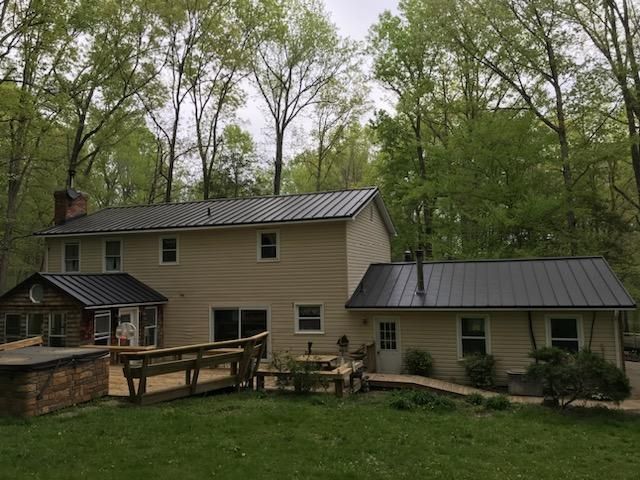 A large house with a metal roof is surrounded by trees.