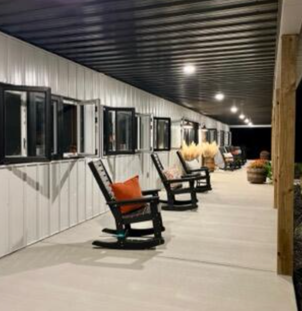 Porch with rocking chairs, windows, white siding, and a dark ceiling.