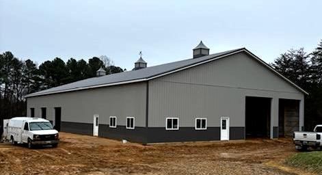 A large pole building with two vans parked in front of it.