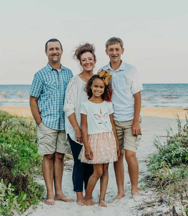 A family is posing for a picture on the beach.