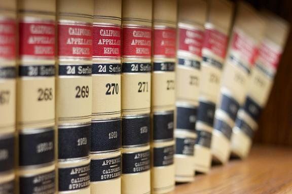 Row of law books on a shelf with red and black labels.