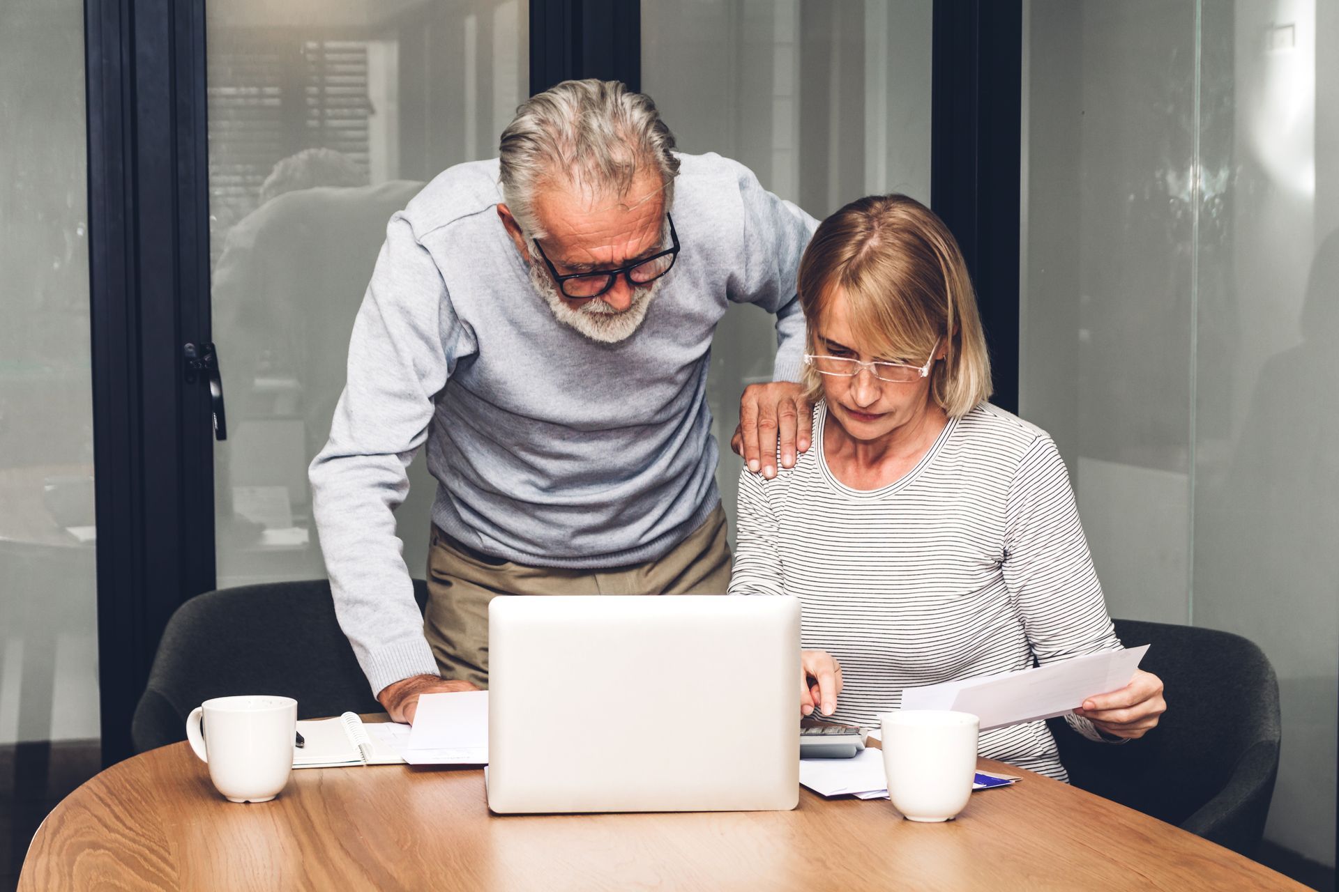 Lawyer shaking hands with client at desk next to scales of justice and a gavel.