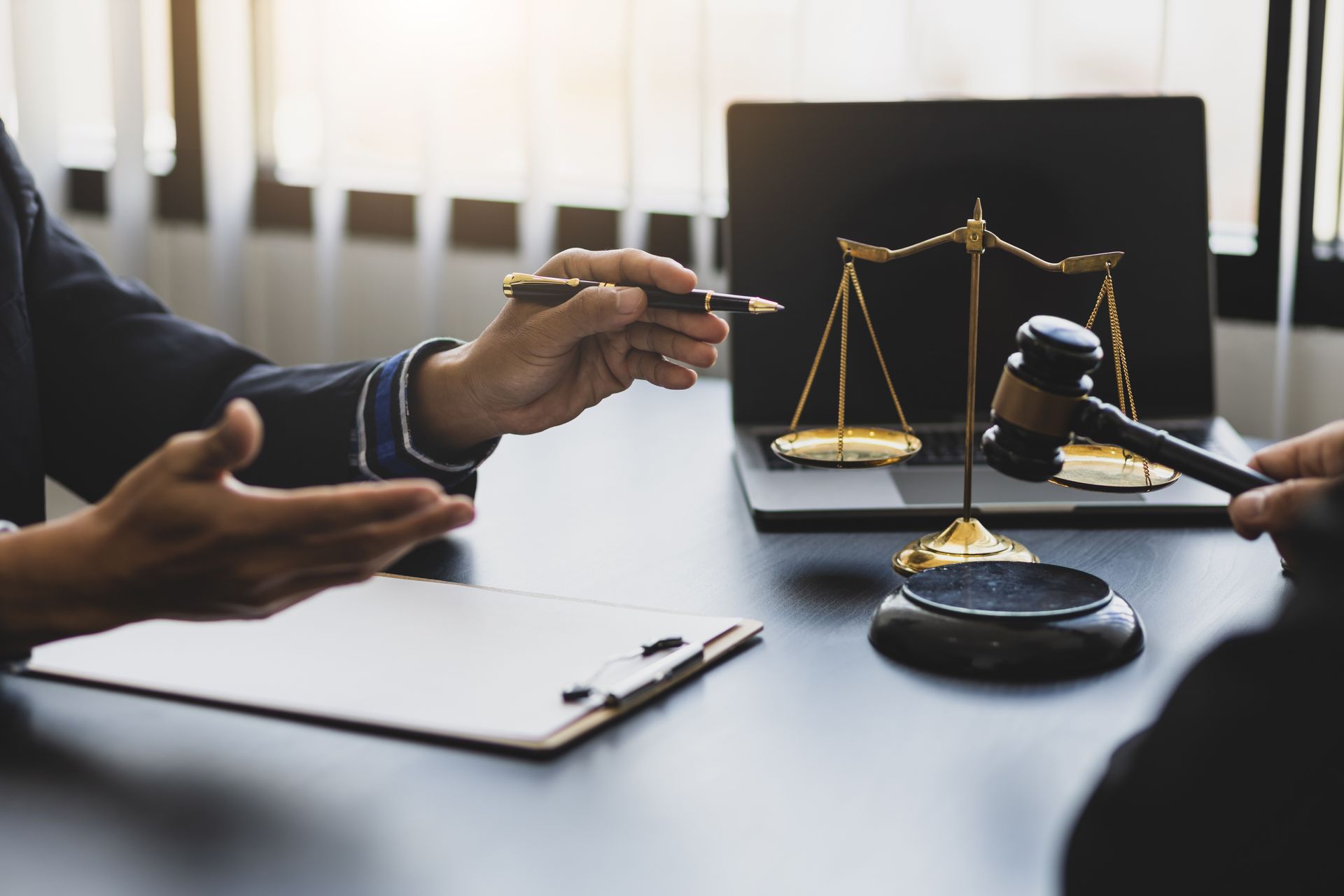 Lawyer’s desk with scales of justice, gavel, and two people discussing a case Lawyer’s desk with scales of justice, gavel, and two people discussing a case