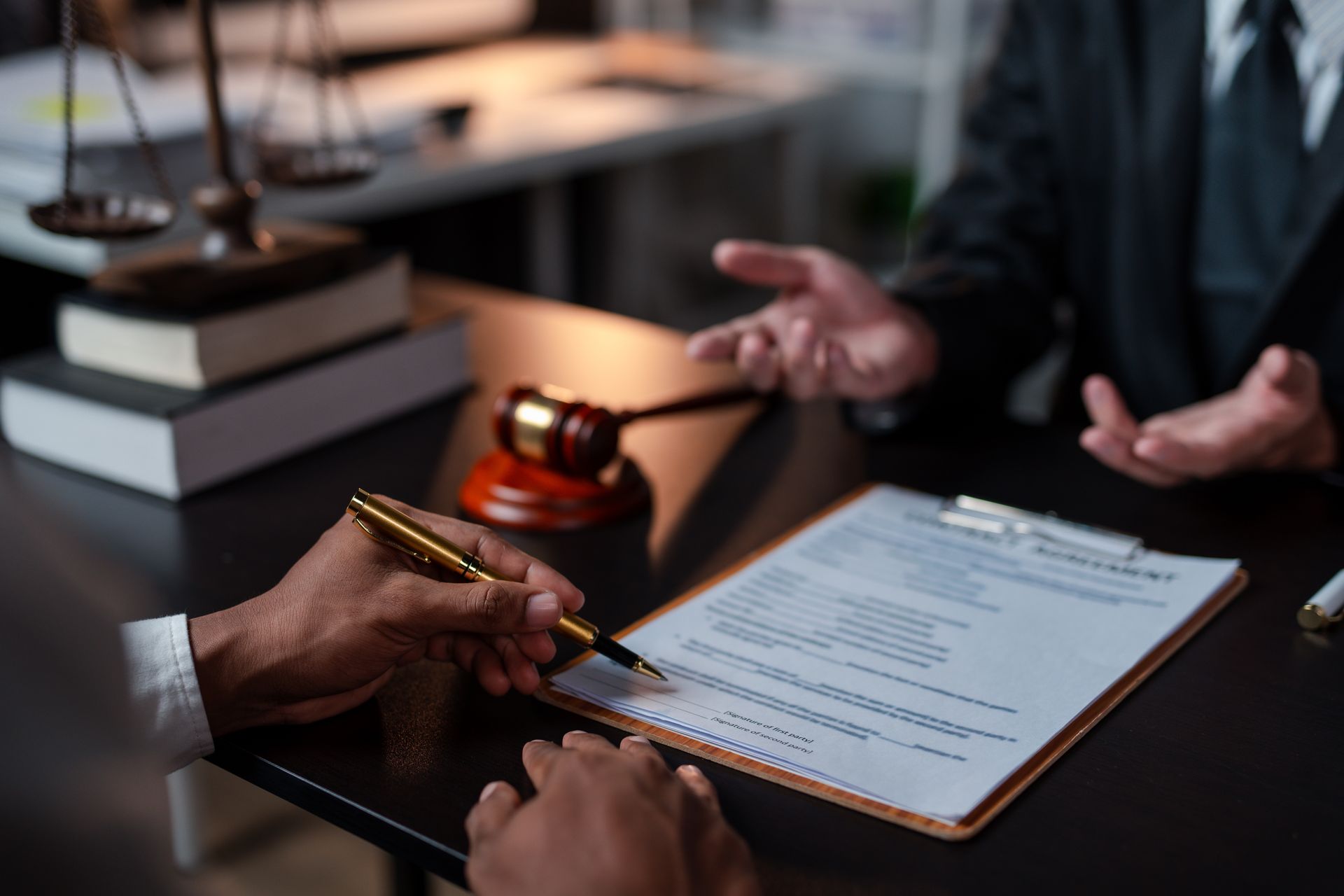 Two people reviewing a signed document at a desk with a pen and gavel nearby Two people reviewing a signed document at a desk with a pen and gavel nearby