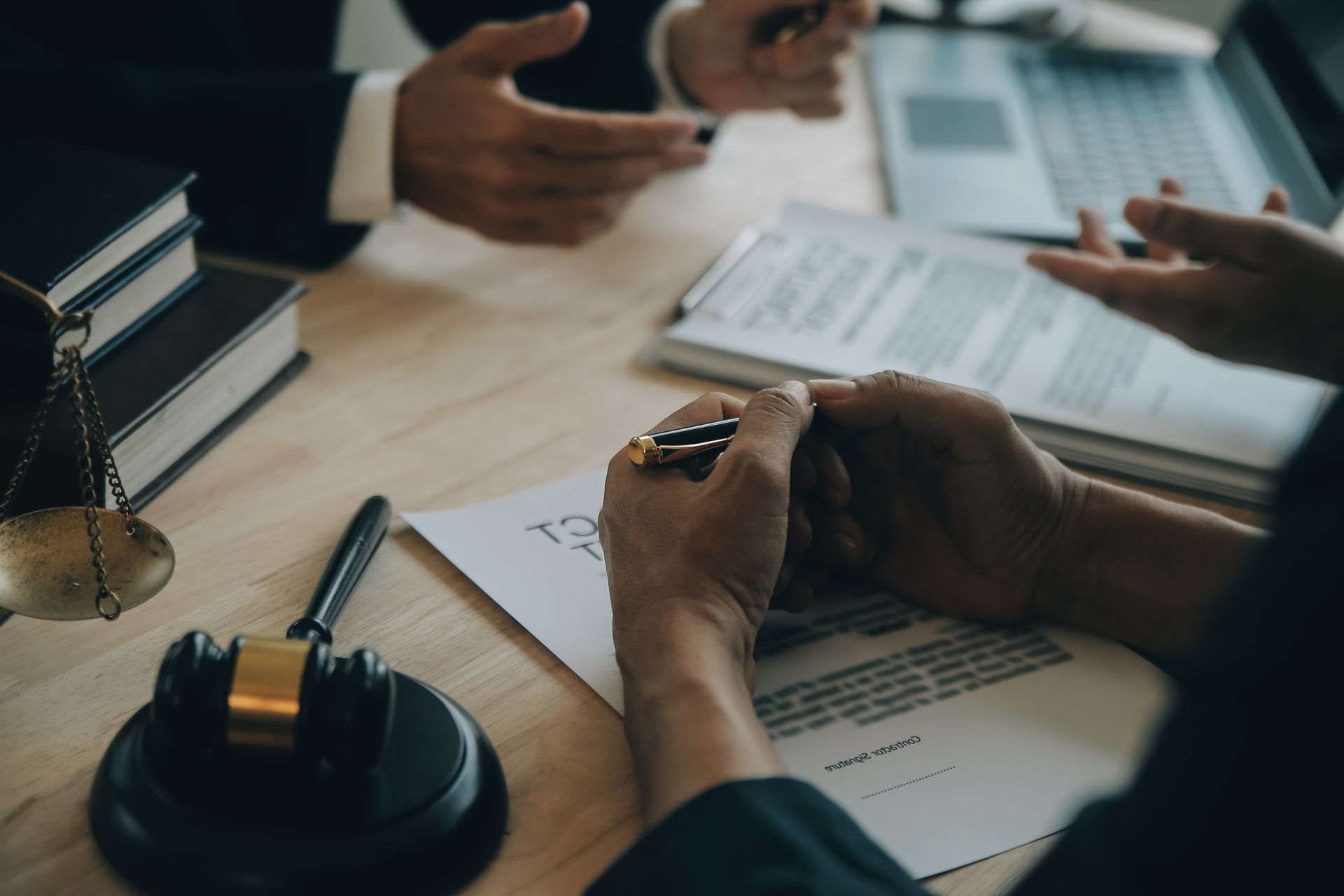 Two people at a desk, reviewing documents. Gavel, scale, and books present, suggesting legal setting.