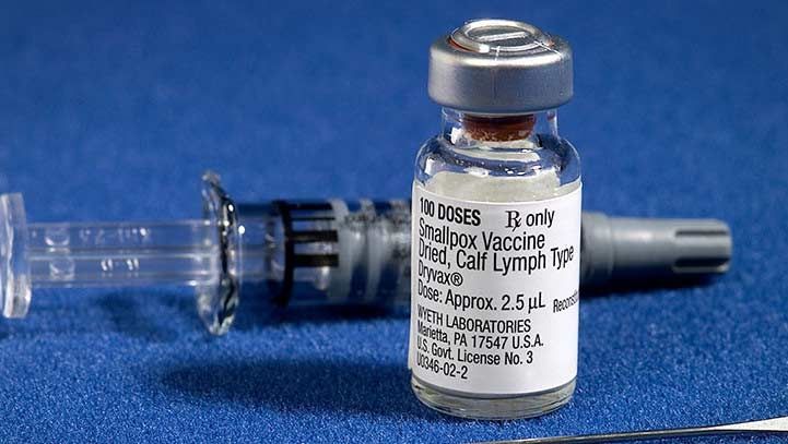 Vaccine vial and syringe on blue surface; labeled
