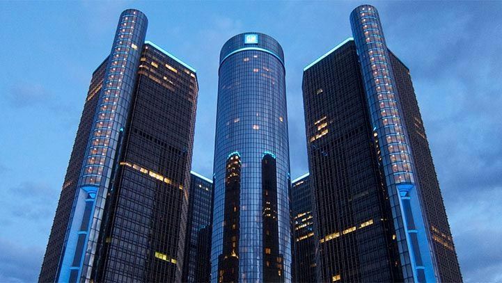 Detroit's Renaissance Center at dusk; three black skyscrapers and a central blue tower against a twilight sky.